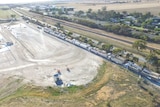 In this aerial shot, a long line of trucks laden with grain can be seen waiting to deliver it to a hippodrome-shaped facility.