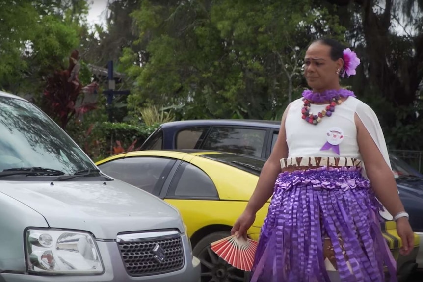 A Leitis walks past a car on the street.