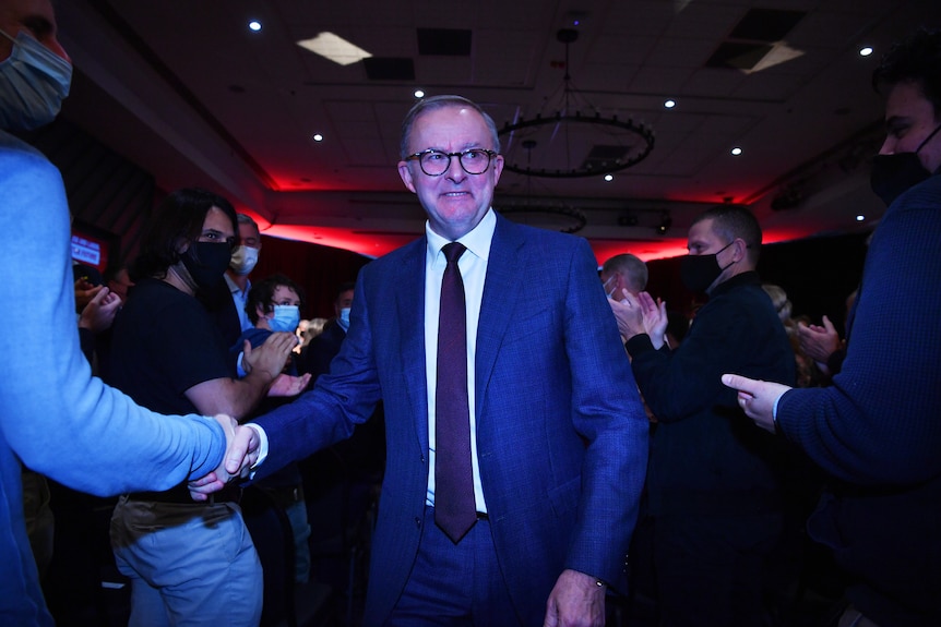 Labor leader Anthony Albanese, wearing a suit, shakes the hands of supporters at a party event.