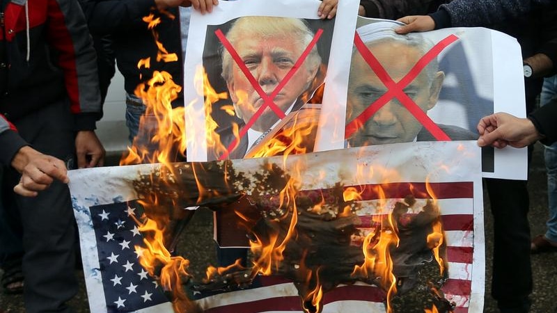 Palestinians burn posters of Benjamin Netanyahu and Donald Trump, along with a picture of the US flag