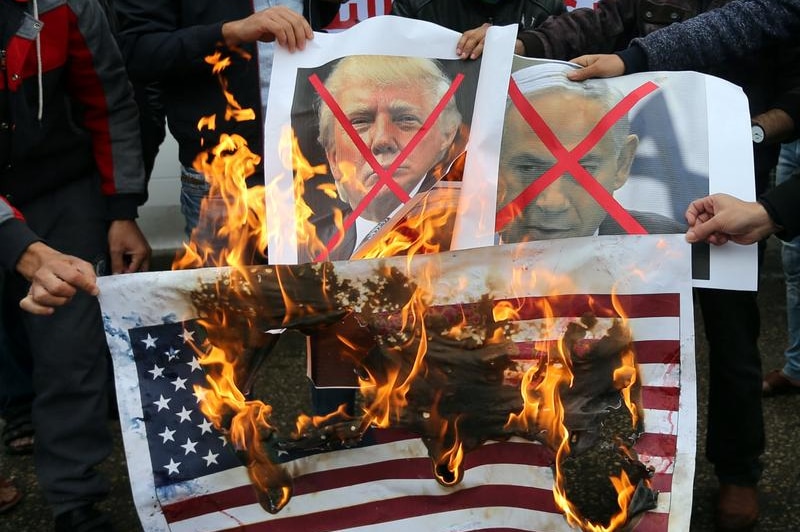 Palestinians burn posters of Benjamin Netanyahu and Donald Trump, along with a picture of the US flag