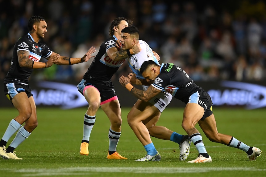 Gold Coast Titans' David Fifita is tackled by Cronulla Sharks players.
