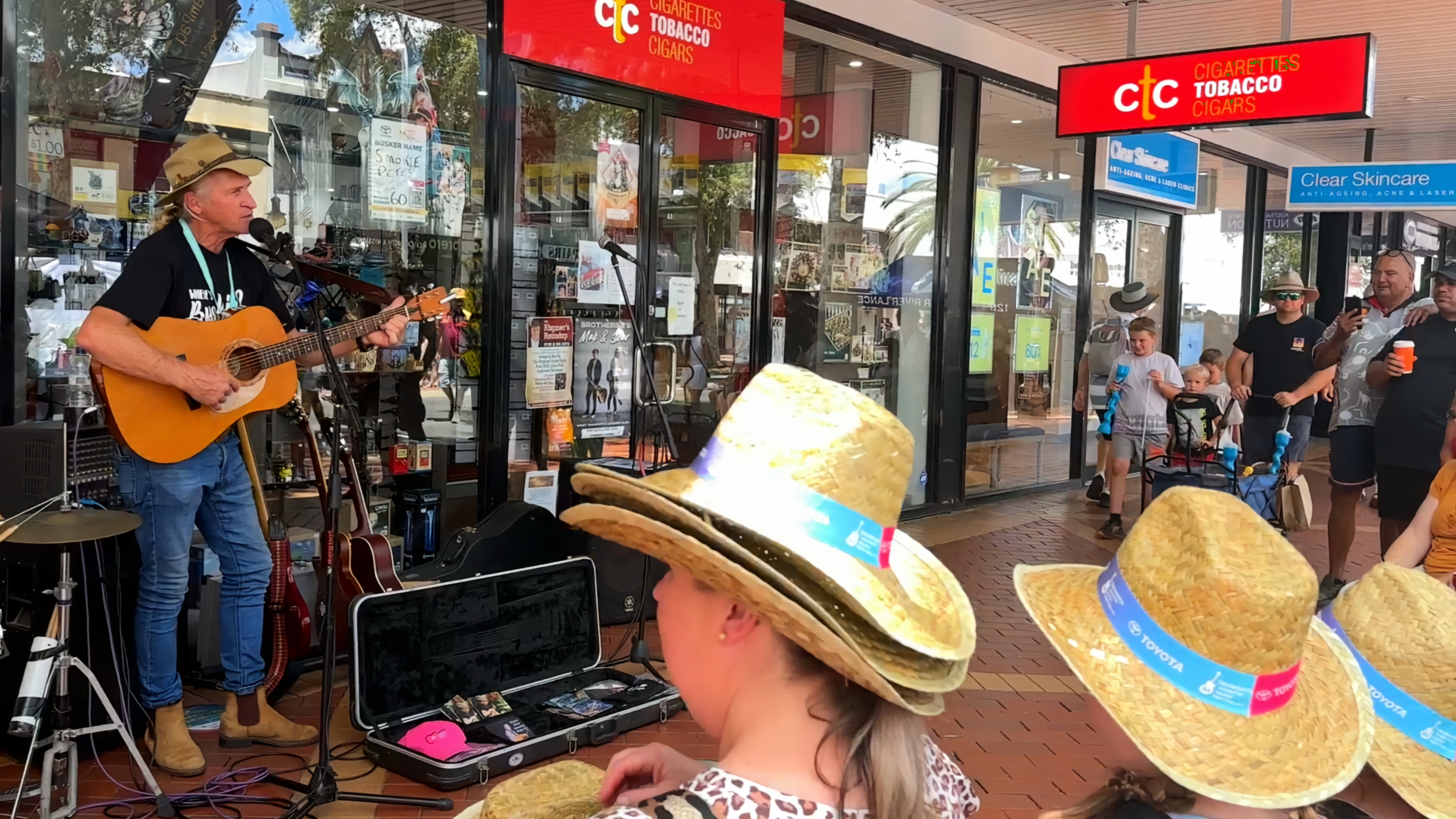 A man busking in front of a shop before a crowd 