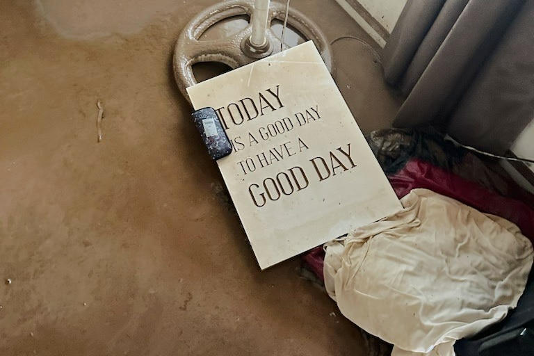 Household items in mud including a sign that says: Today is a good day to have a good day.