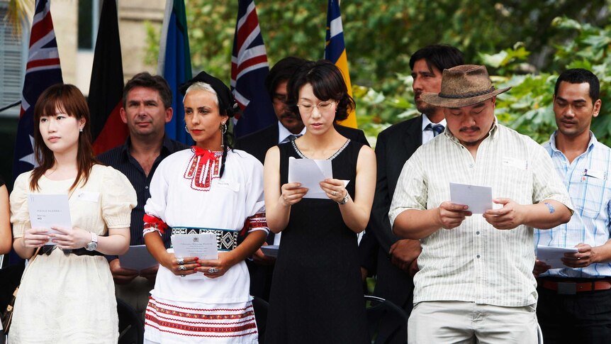 A group of newly inducted Australian citizens stand on a stage, singing the national anthem on Australia Day in 2009.