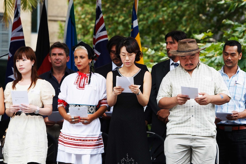 A group of newly inducted Australian citizens stand on a stage, singing the national anthem on Australia Day in 2009.