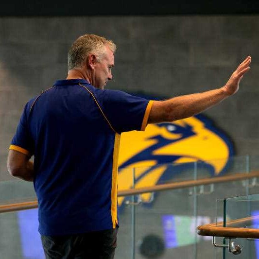 Adam Simpson waving at a media conference.