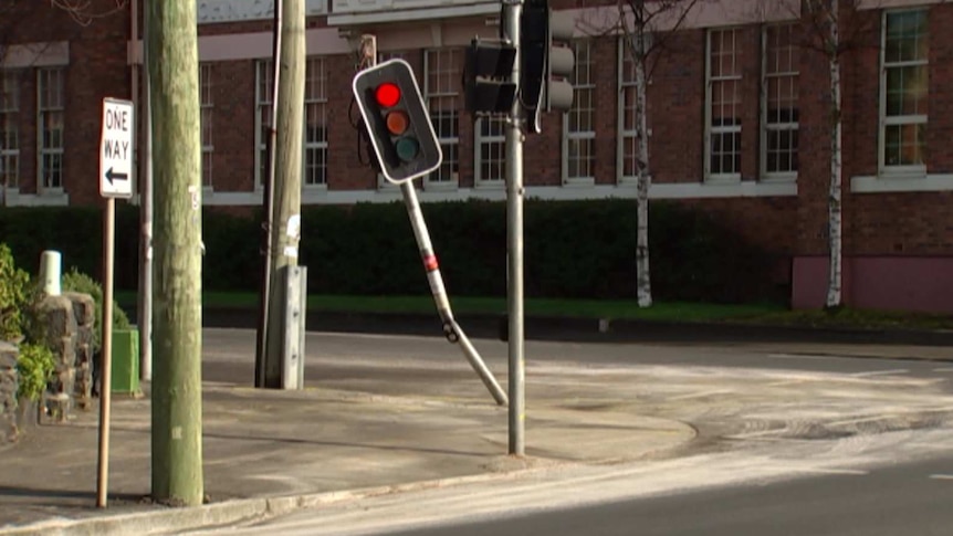 A traffic light is bent from the impact of a motorcycle vs car crash at a city intersection