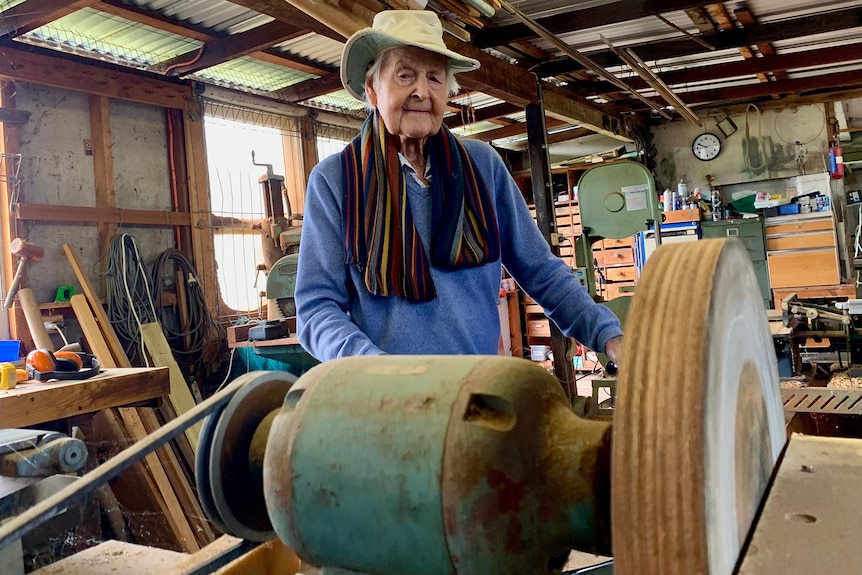 Bert stands behind a lathe in his workshop.