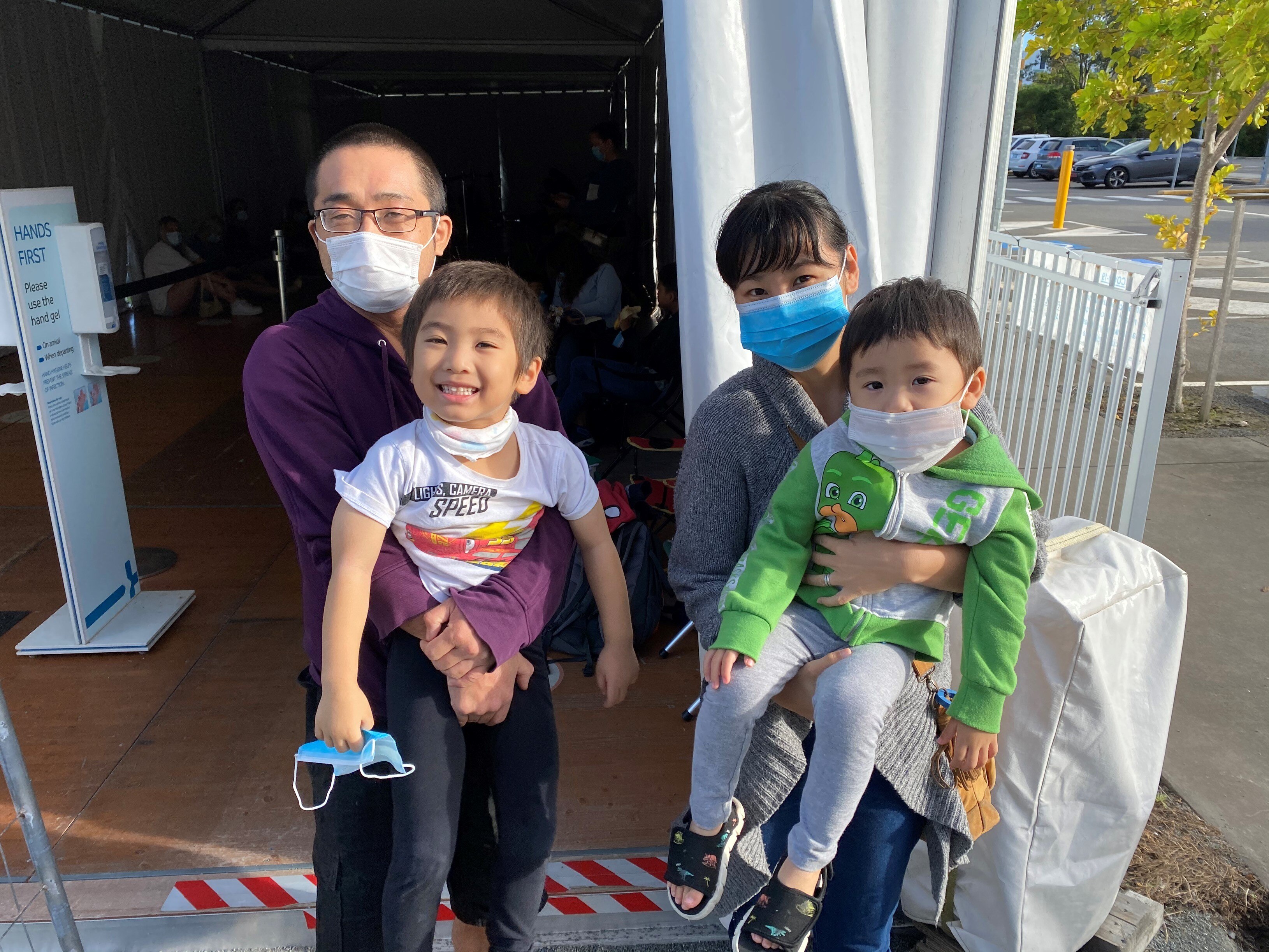 Family of mum and dad wearing masks with two toddlers.