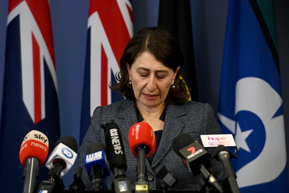 A woman stands in front of several news mics