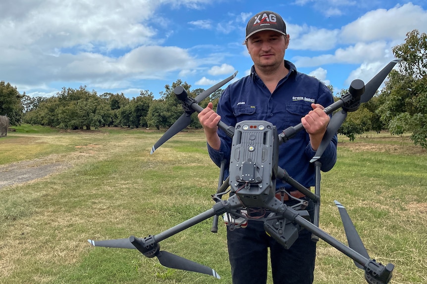 wide shot of a man holding a drone in front of him