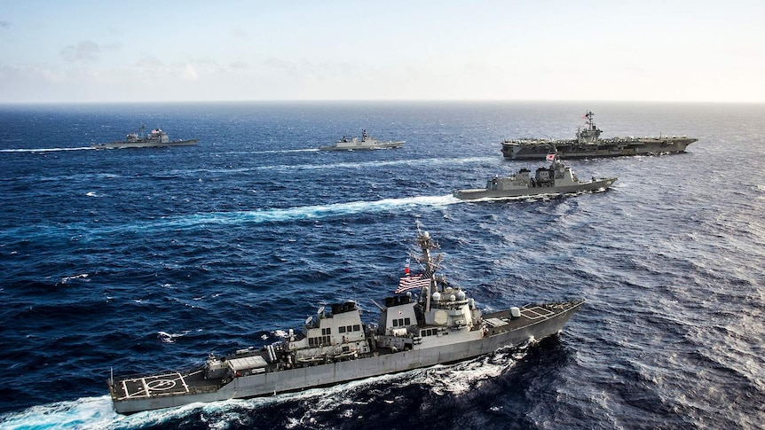 Ships from the US and Indian navies, and Japan Maritime Self-Defense Force transit in formation.