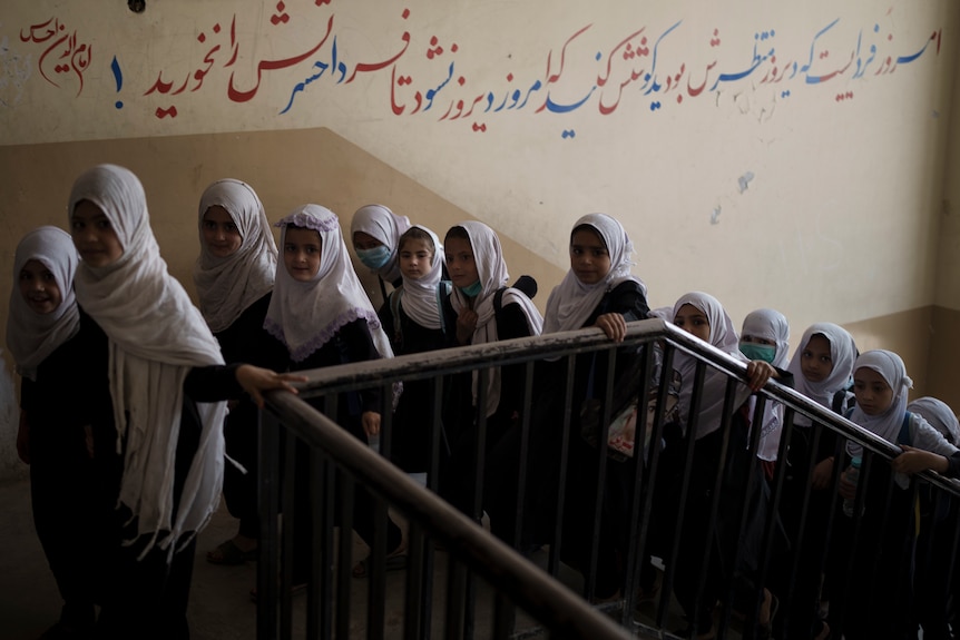 Schoolgirls walk up a flight of stairs.