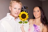 A  young couple hold a sunflower