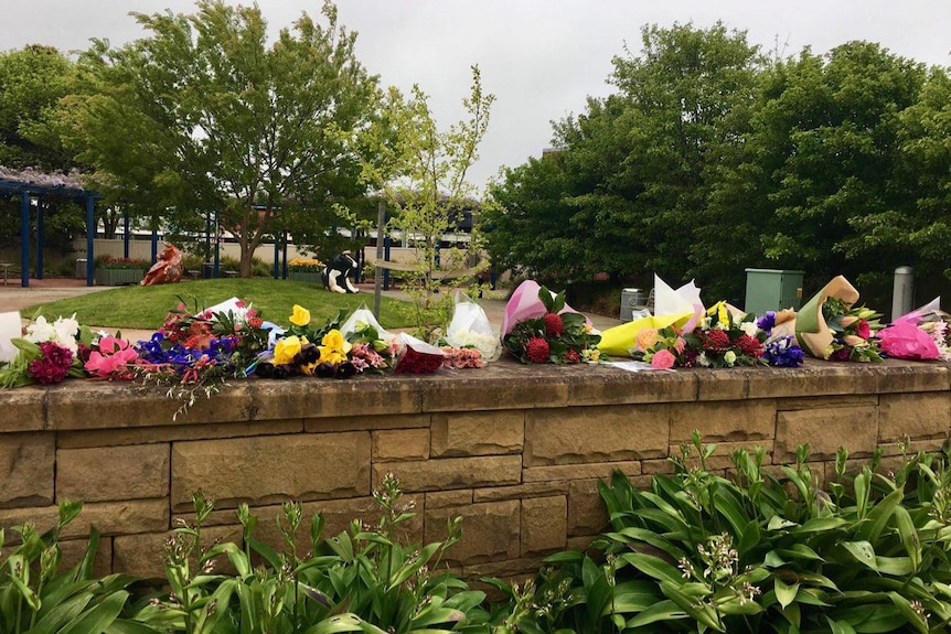 floral bouquets left on top of a low stone wall