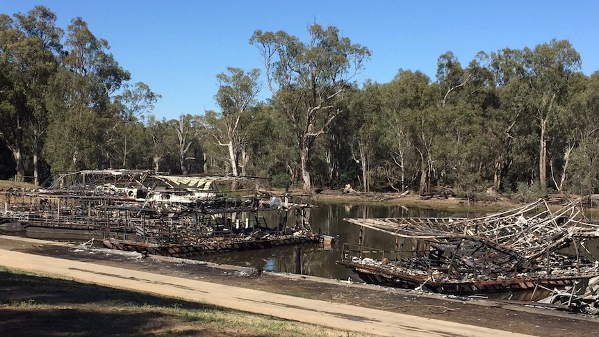 The burned-out remains of several houseboats still afloat on the river.