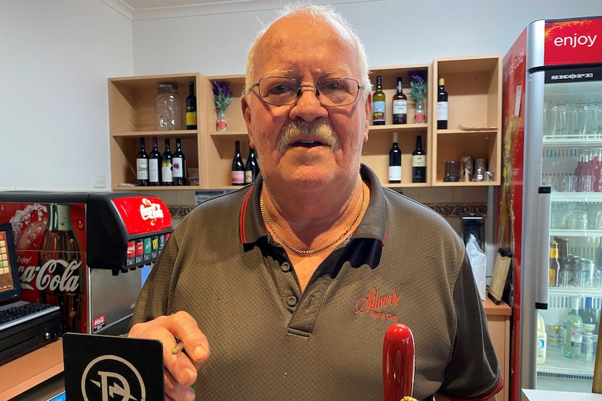 An older gentleman standing behind a bar