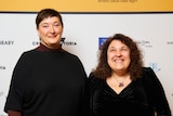 Marisa Sporsaro (right) and Leisa Shelton (left) smiling at the camera in front of a Victorian State Library Fellowship banner.