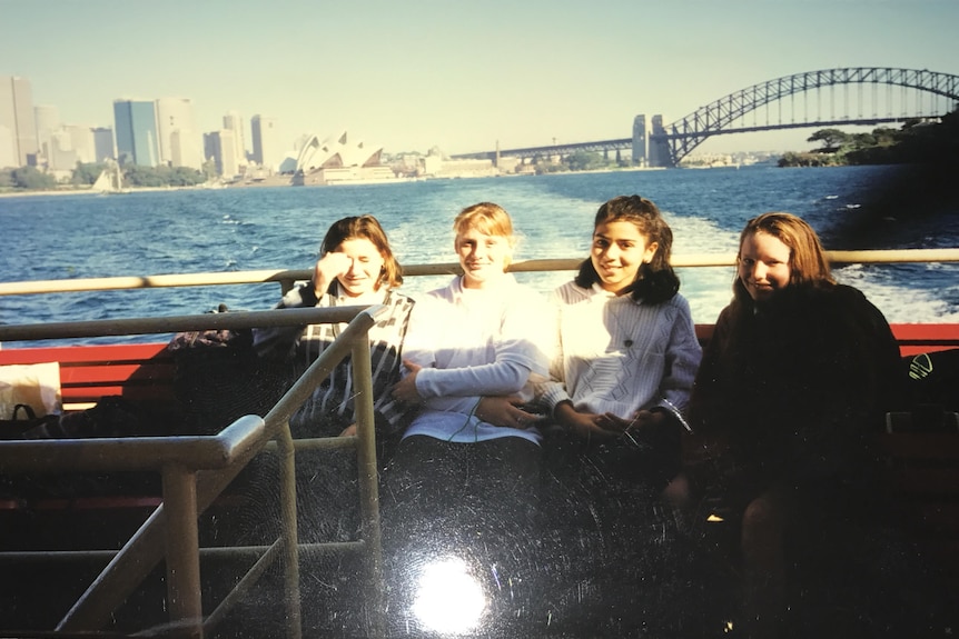 Four girls sitting next to the sea.