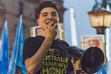 UQ philosophy student Drew Pavlou speaks at a rally with a megaphone.