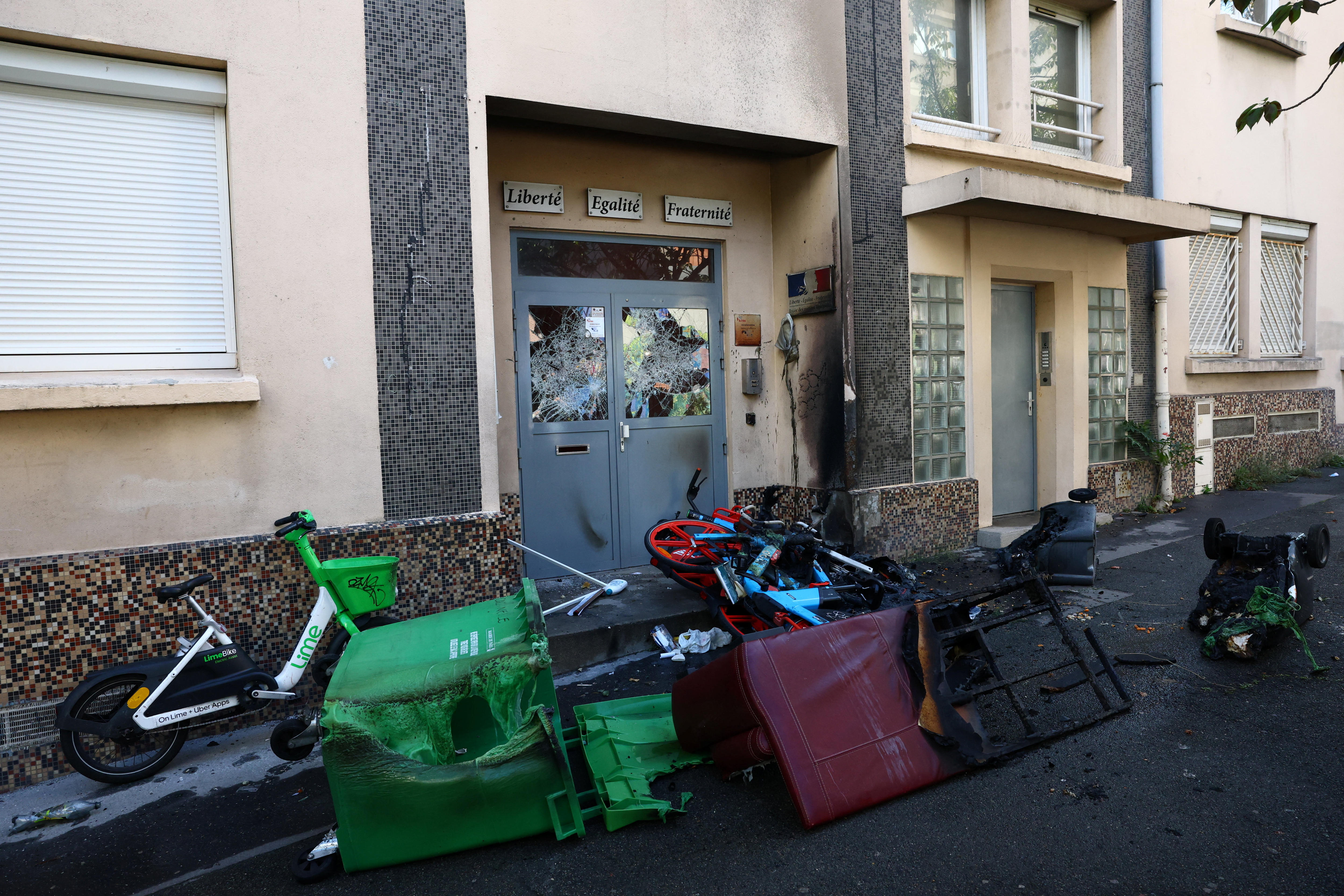 The glass on school doors are smashed in, as bikes and bins are piled up on the street outside.