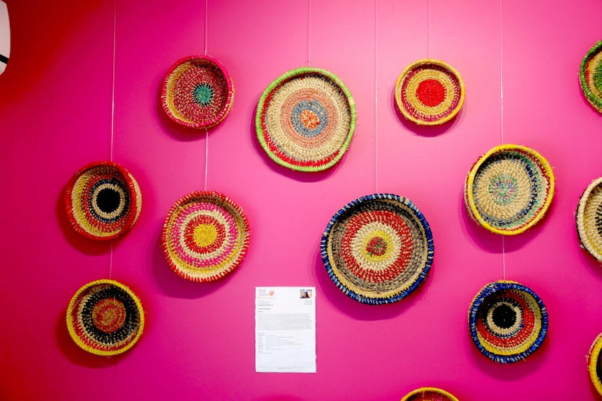 Baskets by Tjanpi desert weavers hang on a wall