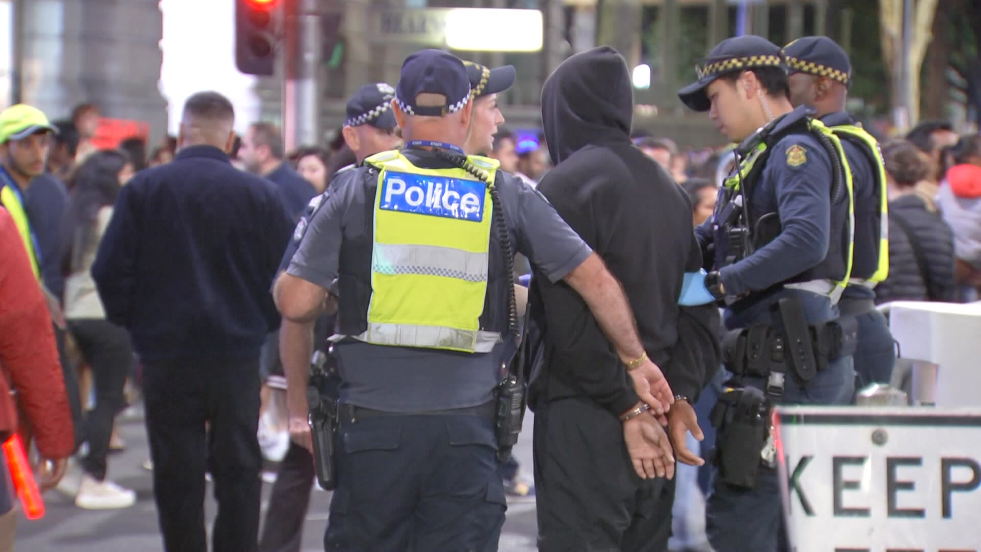 Policiais em uniformes da Marinha e coletes amarelos que dizem "polícia" conversando e andando entre multidões à noite.