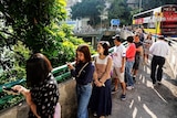A long queue of people stretches down a pathway on a main road as they wait to vote in Hong Kong.