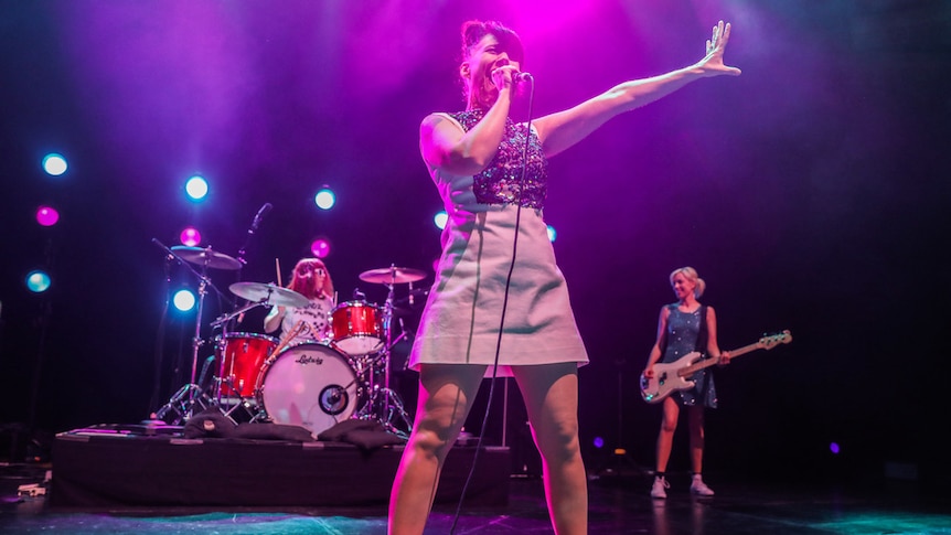 Bikini Kill perform at the Hollywood Palladium in LA. Kathleen Hanna holds her arm up to the left