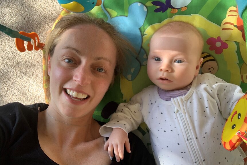 A woman with a child laying down on a mat.