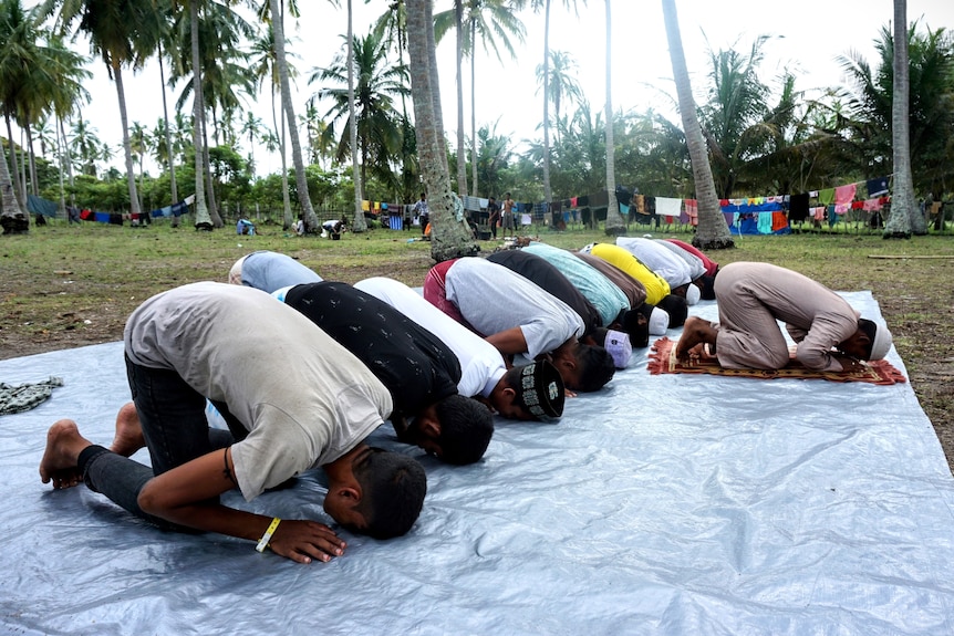 A group of men prostrating while praying together 