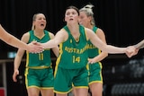 A female basketball player wearing green and yellow high fives her team-mates