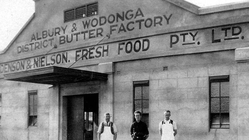 Black and white image of three male workers standing in front of the Holdenson and Nielson Fresh Food dairy company building