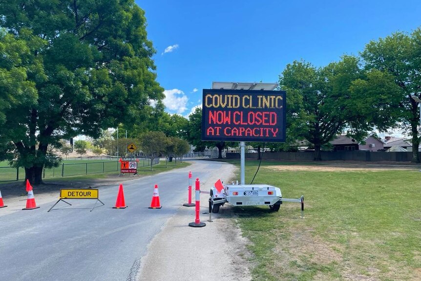 A sign saying "COVID clinic now closed, at capacity".