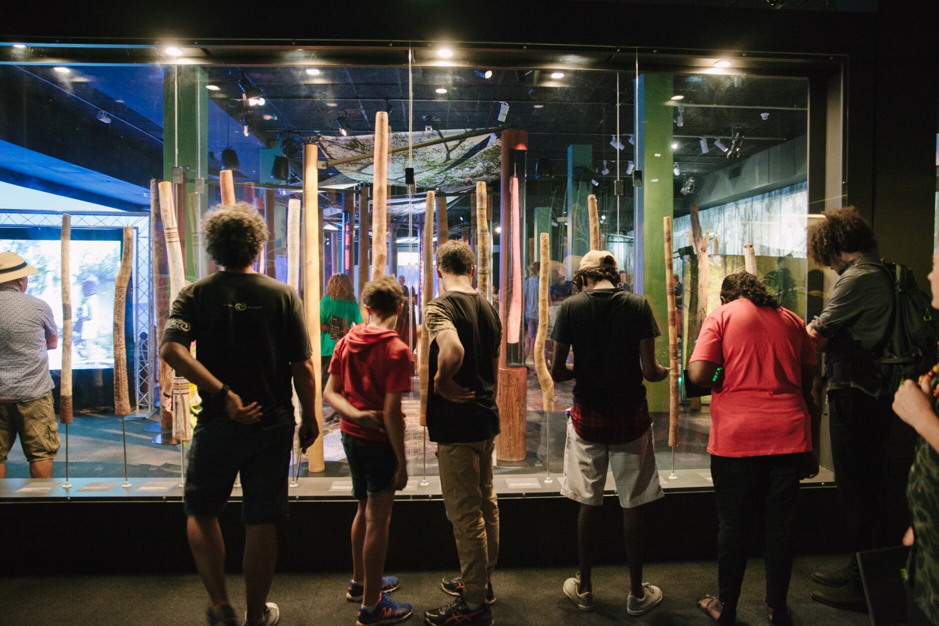  a group of museum goers look at yidakis displayed in a glass case at the South Australian museum