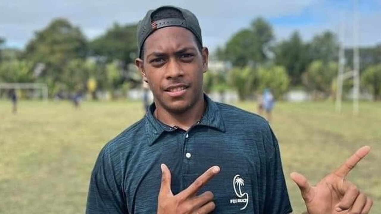 A young man poses for the camera, standing on a field.