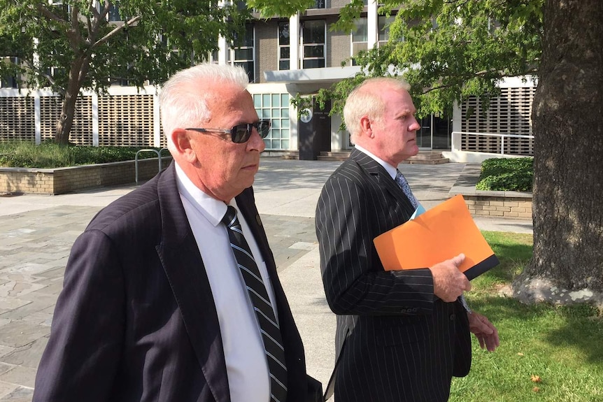 Peter Cuzman leaves court with his lawyers.