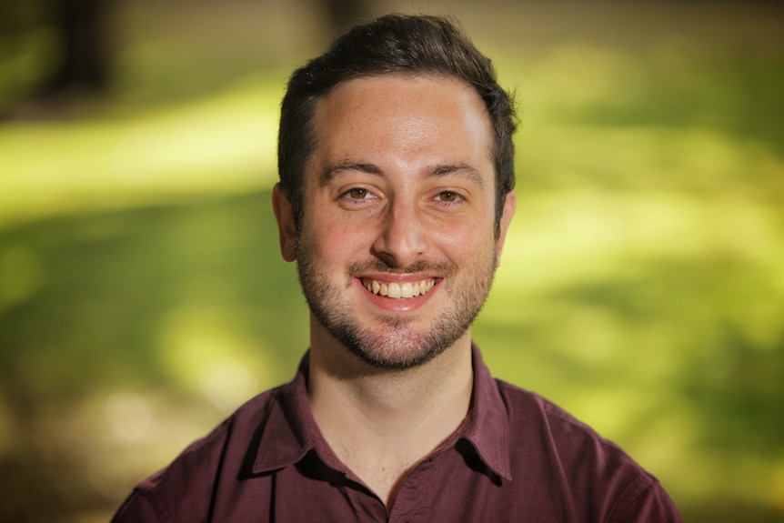 Stephen Bates wearing a maroon business shirt and smiling.