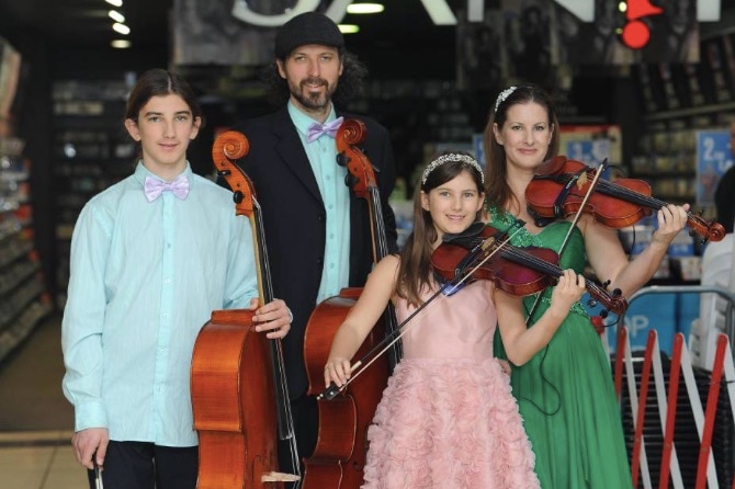 The Moir family stand with their instruments outside a music store.