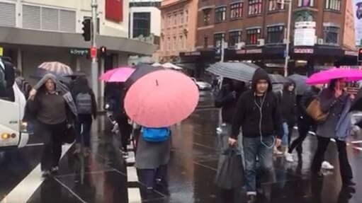 Commuters walking across road with umbrellas