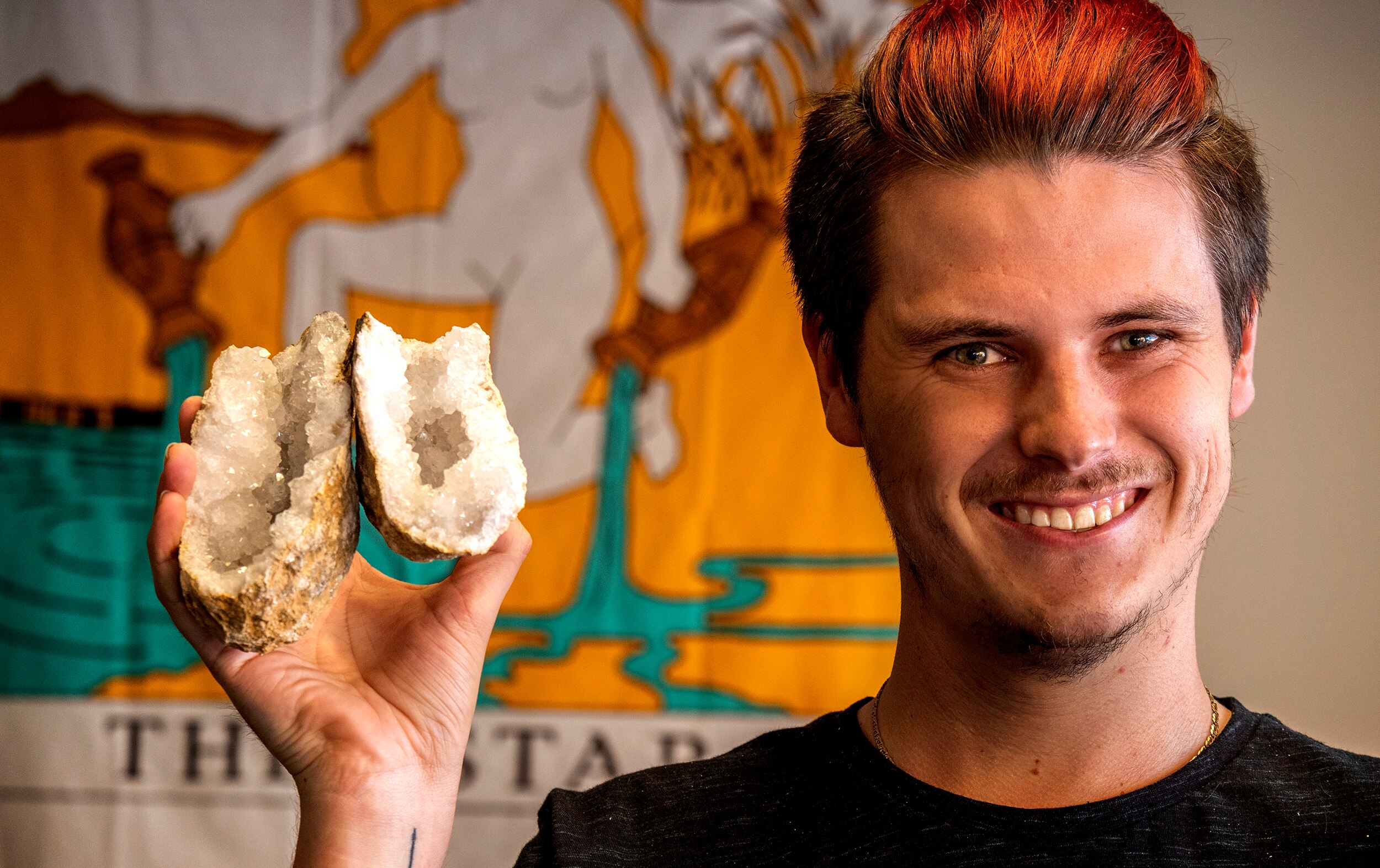 A man holds a geode cracked open revealing crystals.