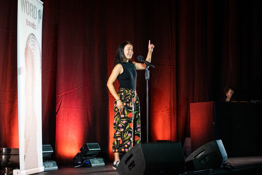 A woman recites a poem on stage