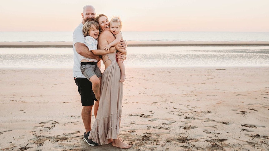 Golden and Chris Whitrod pictured with their kids Tallulah and Finn on a beach at sunset.