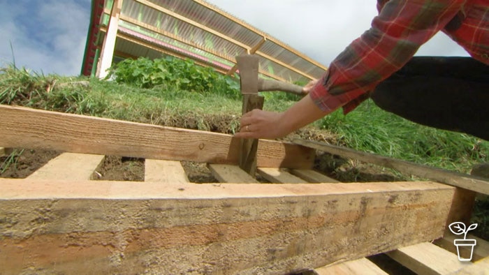 Wooden pallet being hammered onto sloping ground