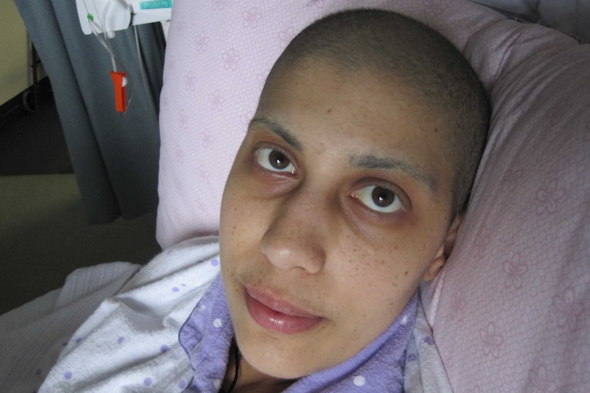 A woman in pyjamas lying down in bed with medical equipment in the background