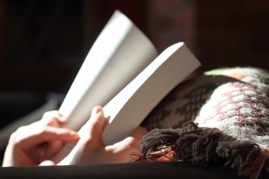 Close image of a book being held on the lap of person reading.