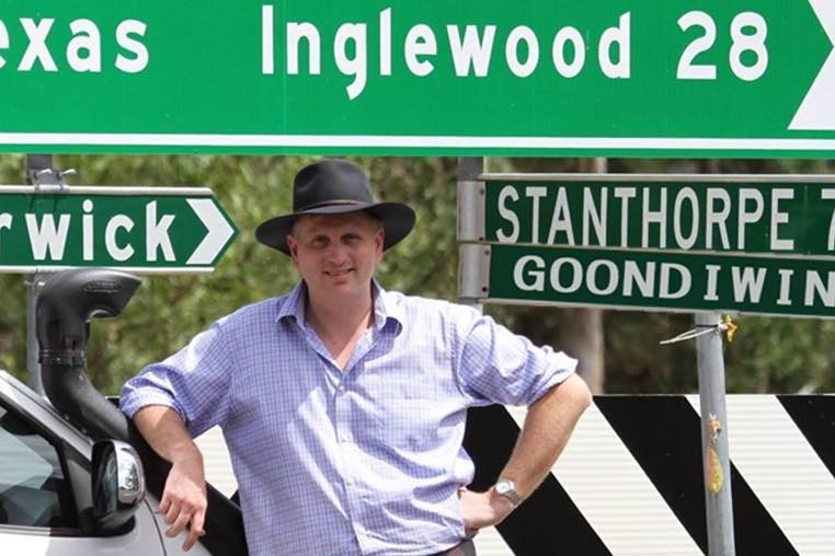 James Lister standing with his hands on his hips in front of road signs pointing to various towns.
