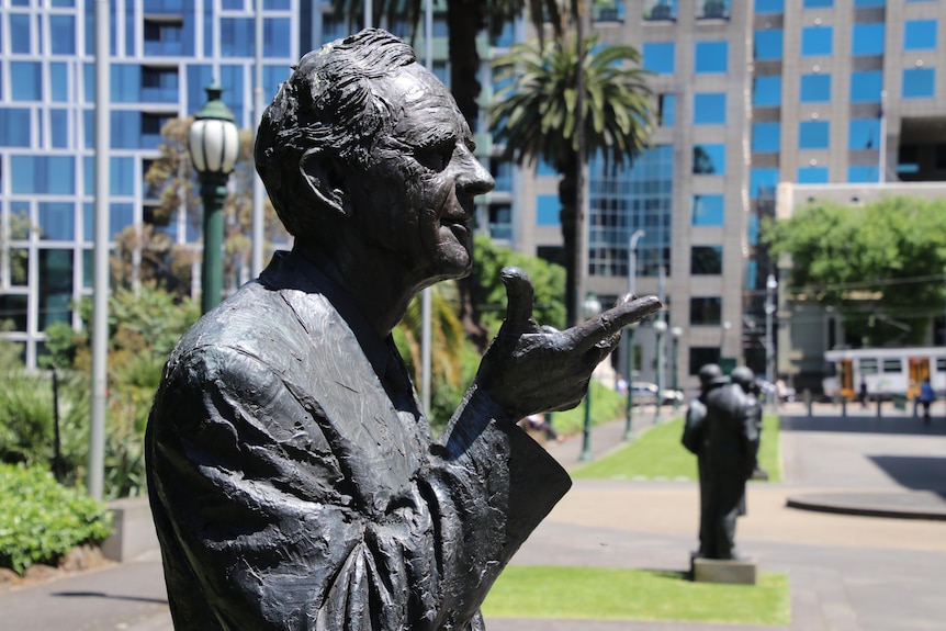 A bronze statue of a man pointing with his finger.