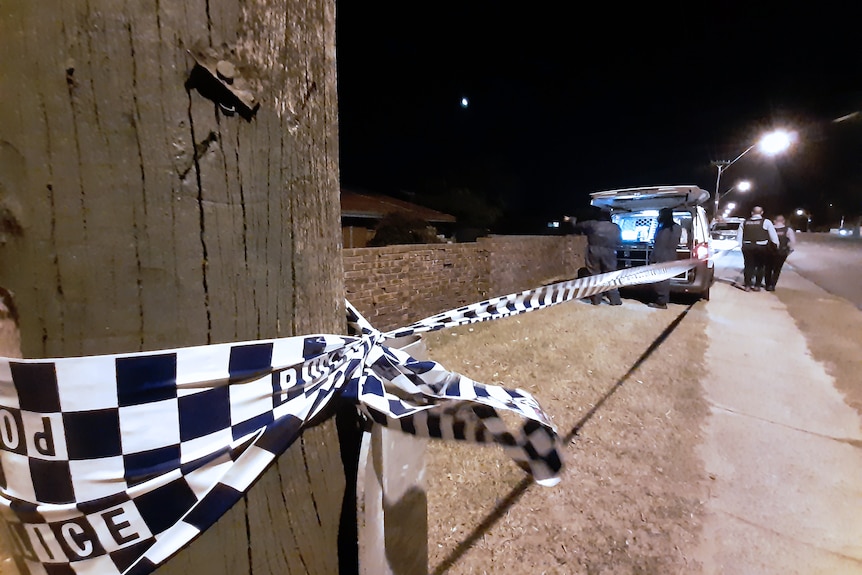 Police tape around a power pole with a police van and detectives on a footpath in the background.